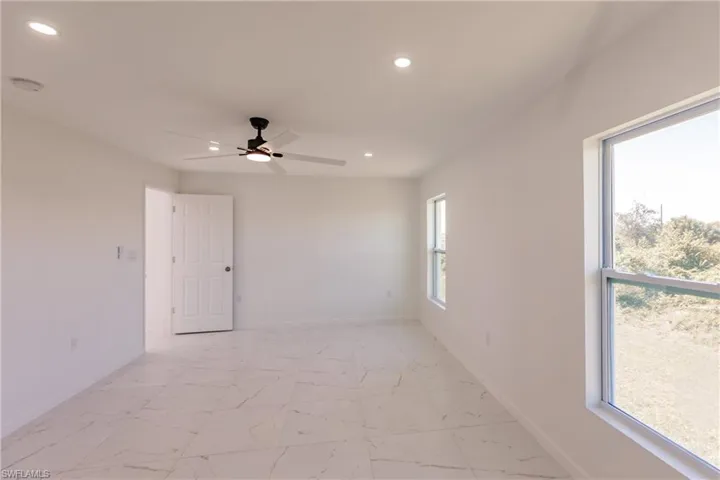Empty room featuring recessed lighting, healthy amount of natural light, ceiling fan, a smoke detector, and light marble finish flooring