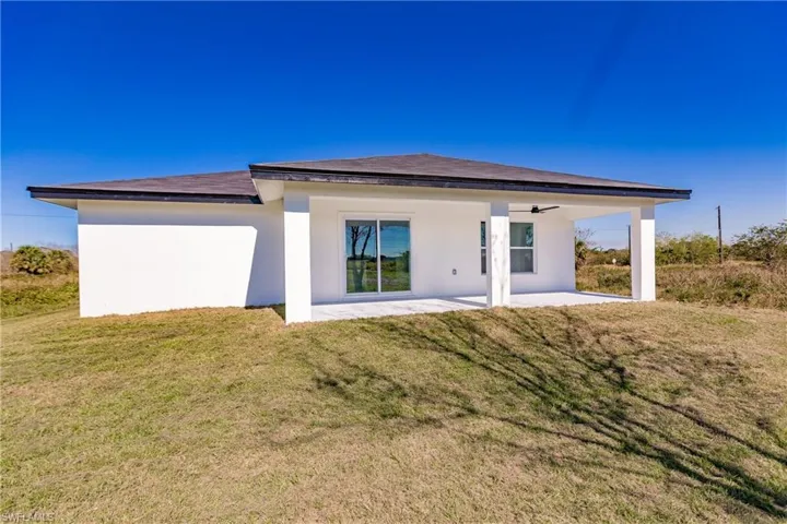 Rear view of house featuring a patio area, a ceiling fan, a yard, and stucco siding