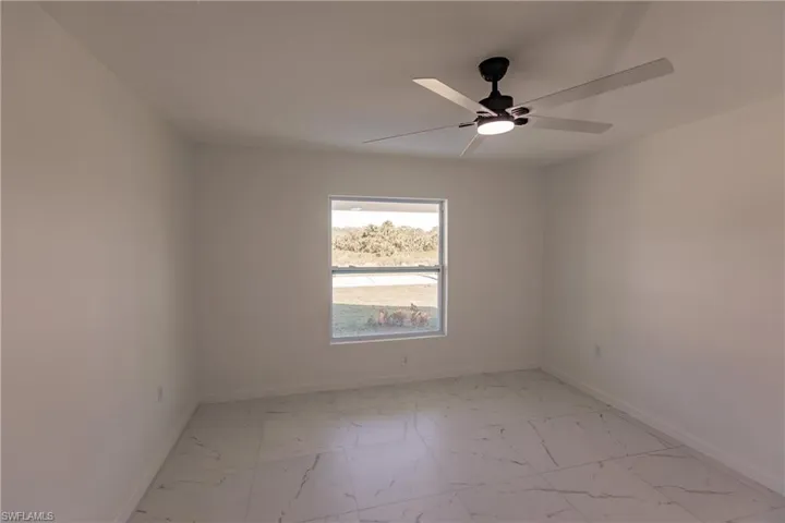 Spare room featuring light marble finish flooring and a ceiling fan
