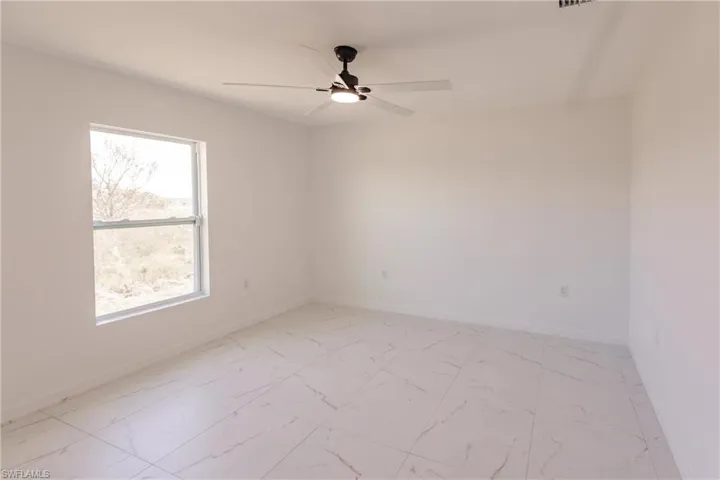 Unfurnished room with a ceiling fan and light marble finish flooring