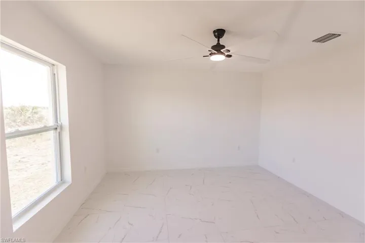 Spare room with light marble finish floors and ceiling fan