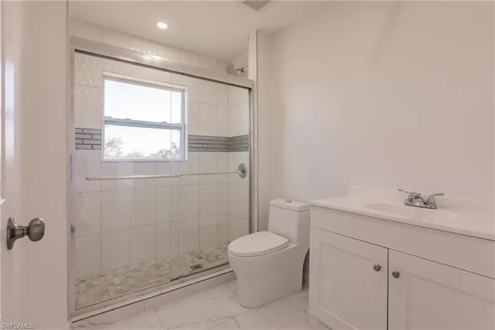 Bathroom with marble finish flooring, vanity, a shower stall, and recessed lighting