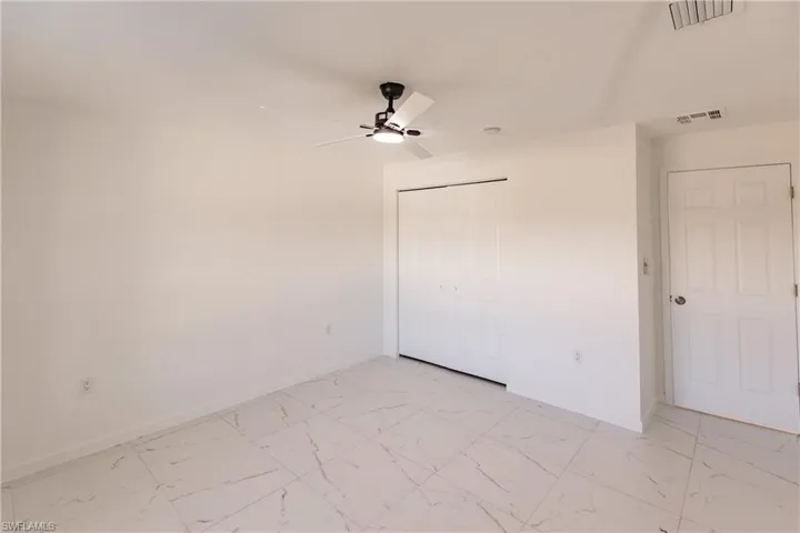 Unfurnished bedroom with light marble finish floors, a closet, and a ceiling fan