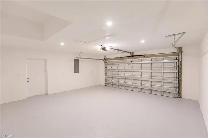 Garage with recessed lighting, a garage door opener, and electric panel