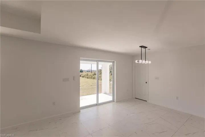 Unfurnished room featuring light marble finish floors and a chandelier