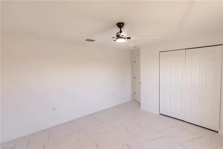 Unfurnished bedroom featuring light marble finish flooring, a closet, and ceiling fan