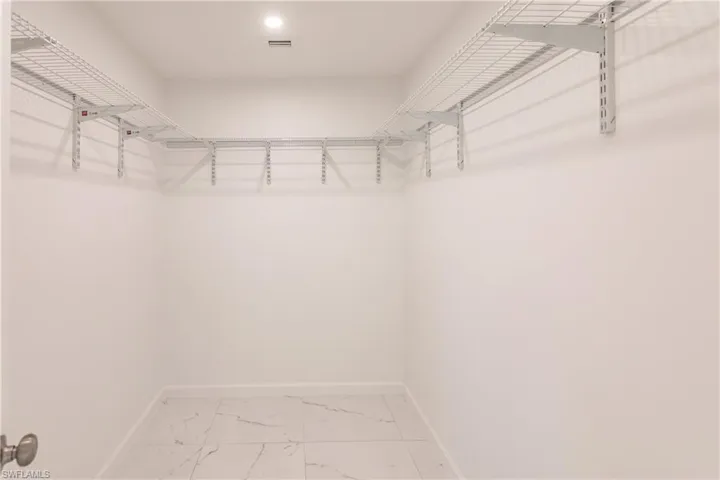 Spacious closet featuring marble finish floors