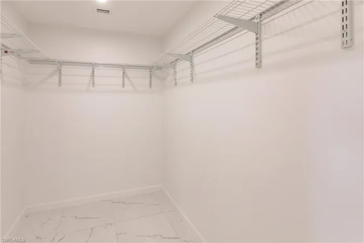 Spacious closet featuring light marble finish flooring