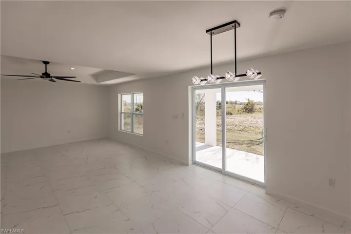 Spare room featuring light marble finish floors, a ceiling fan, a chandelier, and a smoke detector