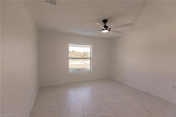 Empty room featuring a ceiling fan and light marble finish flooring