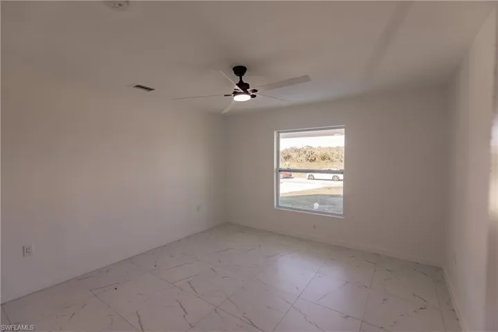 Empty room with light marble finish floors and ceiling fan