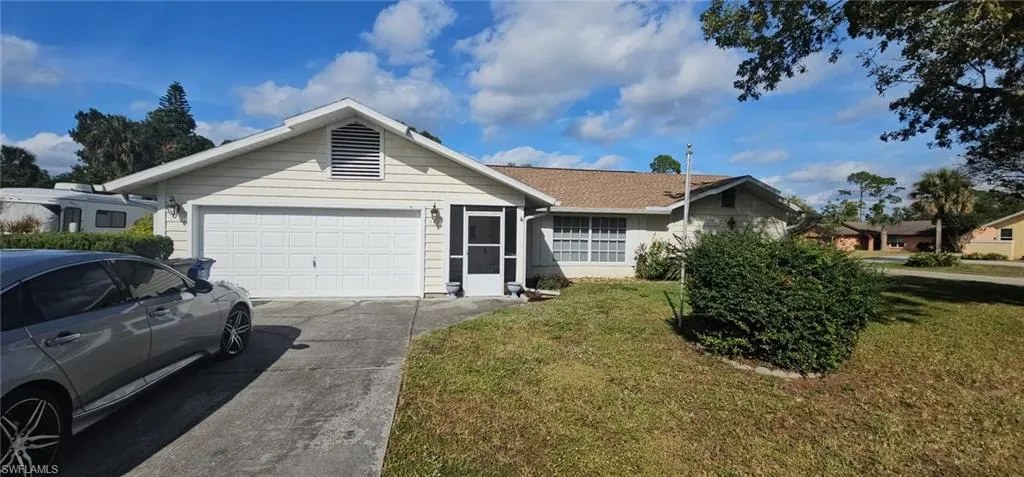 Ranch-style home featuring a front lawn, concrete driveway, and an attached garage
