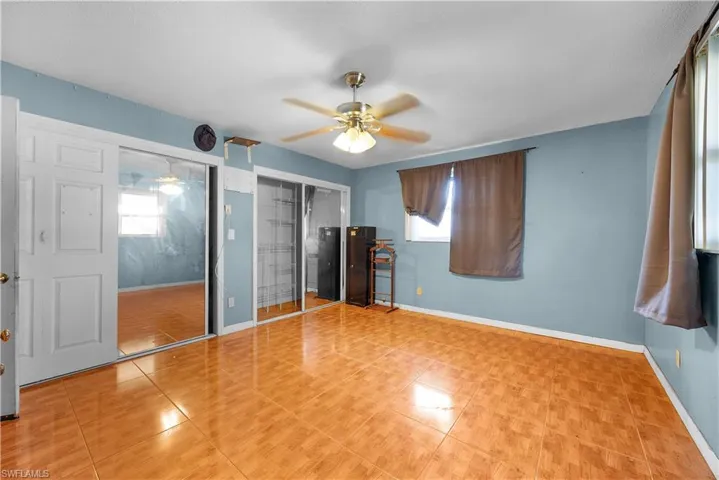 Unfurnished bedroom with multiple windows, light tile patterned floors, and ceiling fan