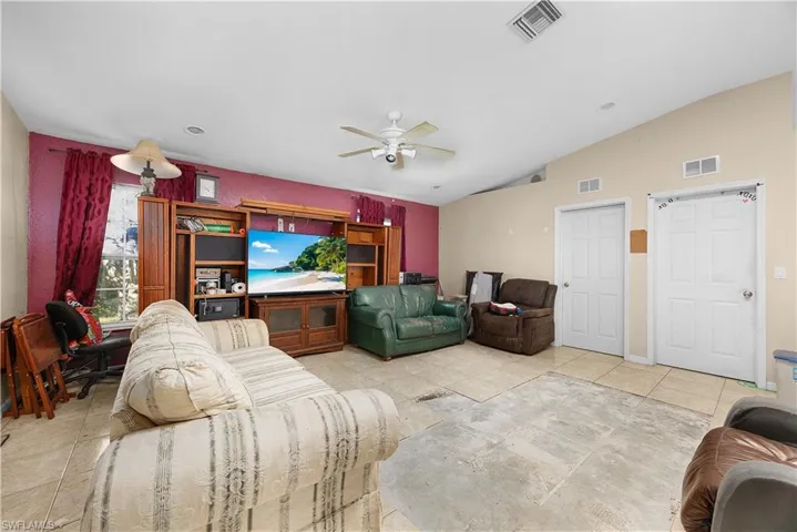 Living area featuring light tile patterned flooring, lofted ceiling, and a ceiling fan
