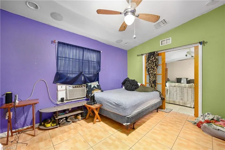Tiled bedroom featuring lofted ceiling, ceiling fan, and cooling unit