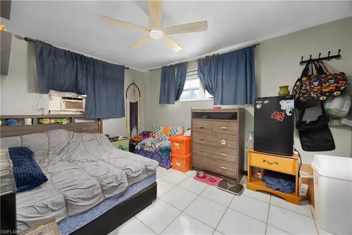 Bedroom featuring light tile patterned floors, a ceiling fan, and cooling unit