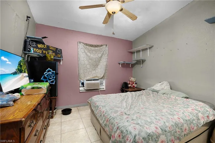 Bedroom featuring light tile patterned floors, ceiling fan, and cooling unit