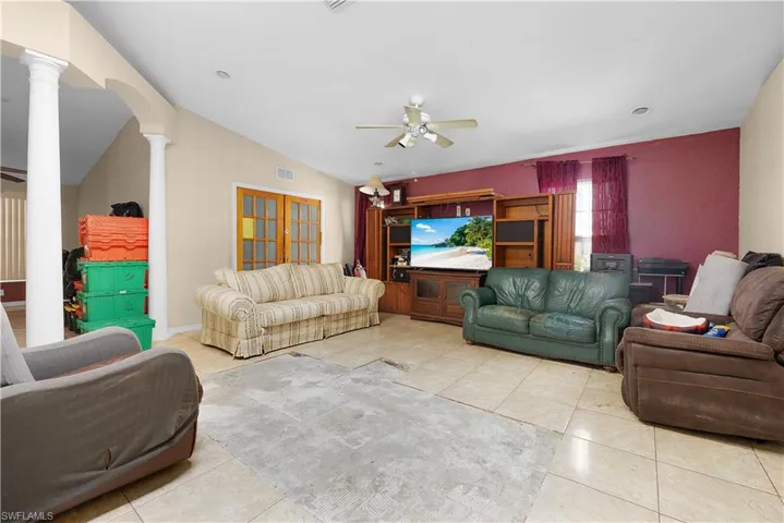 Living room featuring ceiling fan, vaulted ceiling, and tile patterned floors
