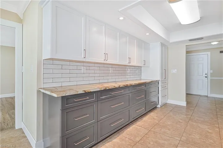Two tone kitchen featuring two tone cabinets, crown molding, backsplash, recessed lighting, and light tile patterned floors