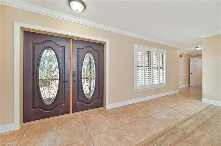Entryway featuring crown molding and light tile patterned floors