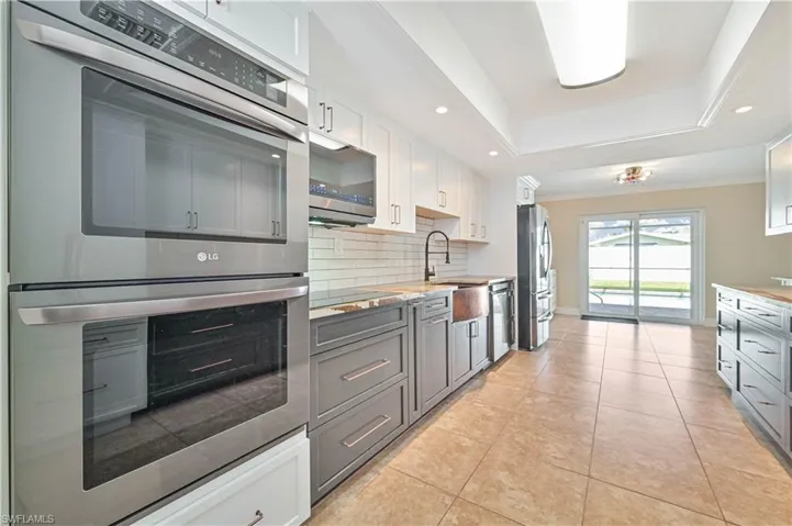 Kitchen with stainless steel appliances, two tone color scheme, recessed lighting, crown molding, and light tile patterned floors