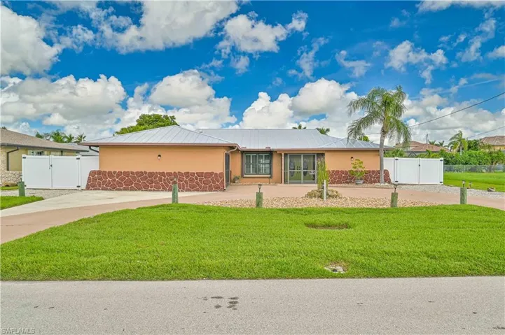 Single story home featuring a gate, a metal roof, and stucco siding