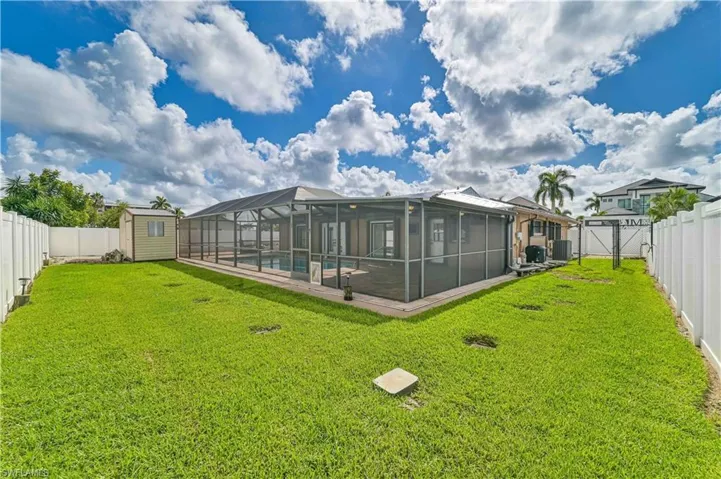 Rear view of house with a fenced backyard, a storage unit, a gate, and a lanai