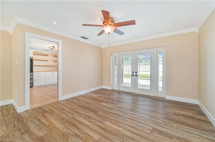Unfurnished room featuring french doors, crown molding, a ceiling fan, and light wood finished floors