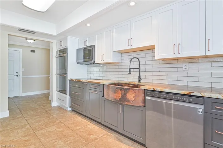 Dual tone kitchen with two tone cabinetry, stainless steel appliances, recessed lighting, backsplash, and light tile patterned floors