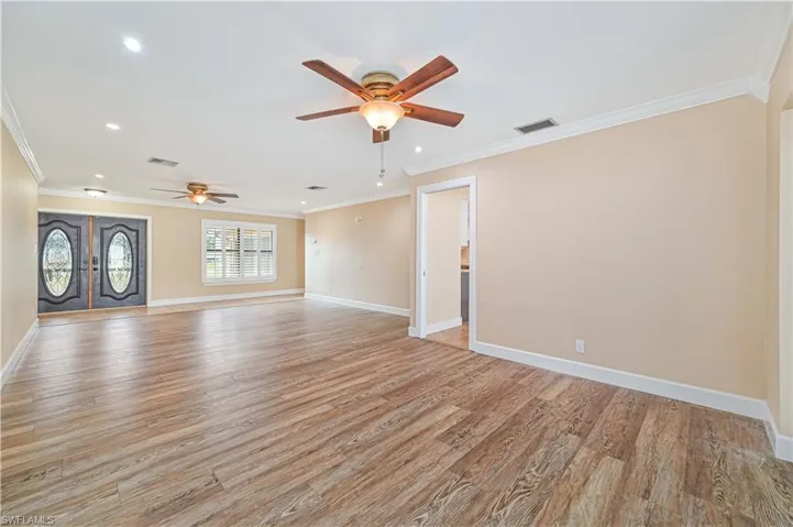 Unfurnished living room with light wood-style flooring, crown molding, recessed lighting, ceiling fan, and french doors