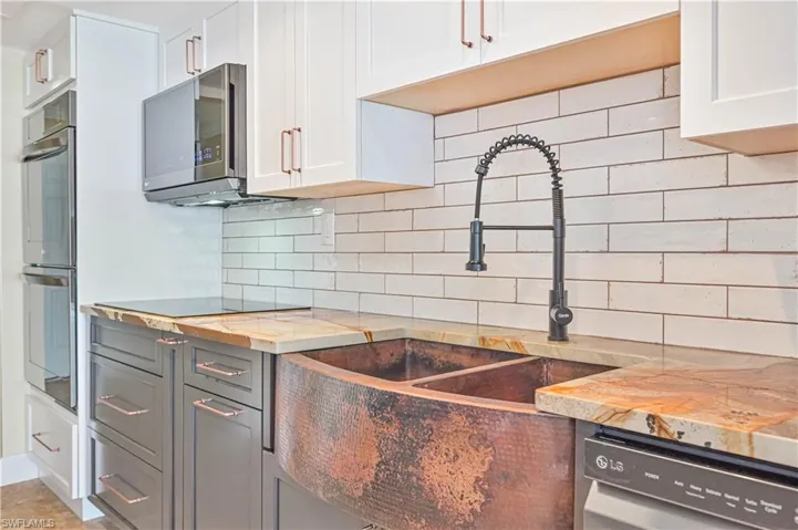 Dual tone kitchen with backsplash, stainless steel appliances, and two tone color scheme