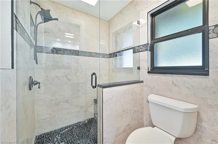 Full bathroom with a stall shower and tile walls