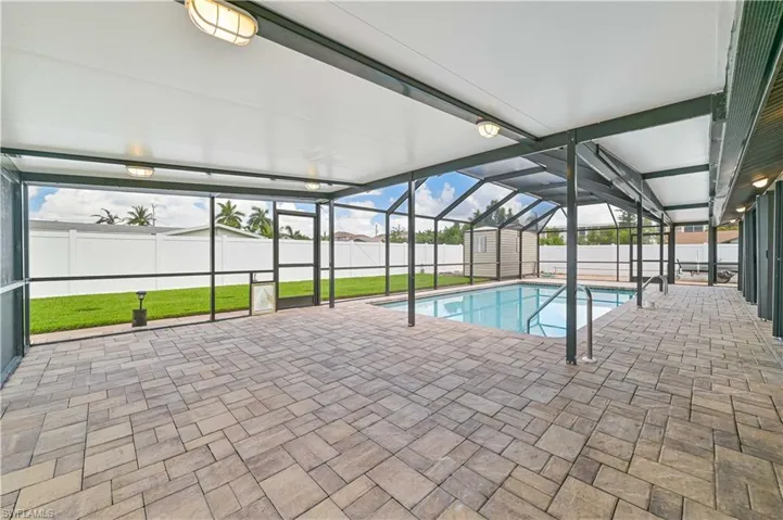View of swimming pool featuring a sunroom, a shed, a lanai, patio surround, and a fenced backyard