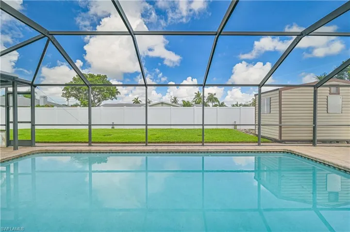 View of swimming pool with a sunroom, a fenced backyard, a lanai, and an outbuilding