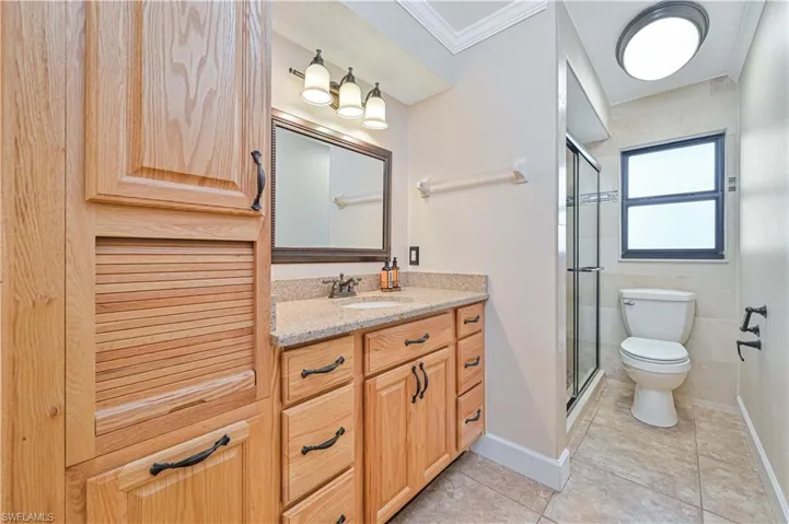 Bathroom with vanity, a stall shower, light tile patterned floors, and crown molding