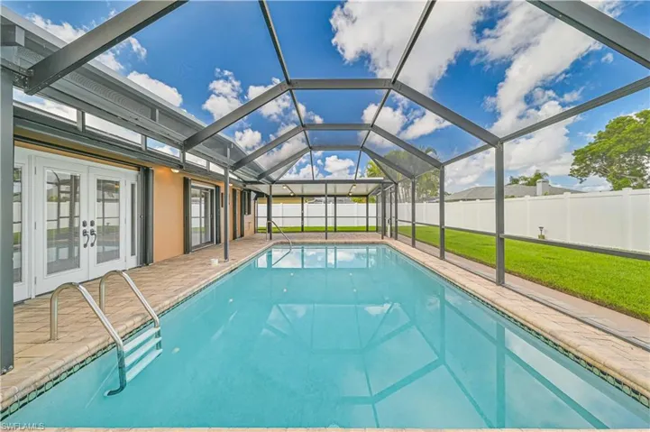 View of swimming pool with a fenced backyard, a sunroom, glass enclosure, french doors, and patio surround