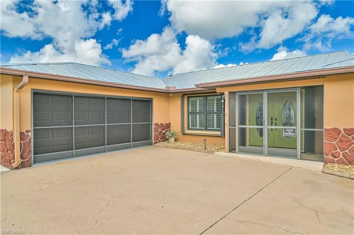 View of front of house with stucco siding, a metal roof, and concrete driveway