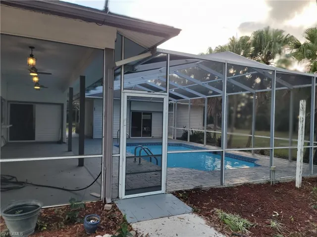 Swimming pool featuring a lanai, a patio, and a sunroom