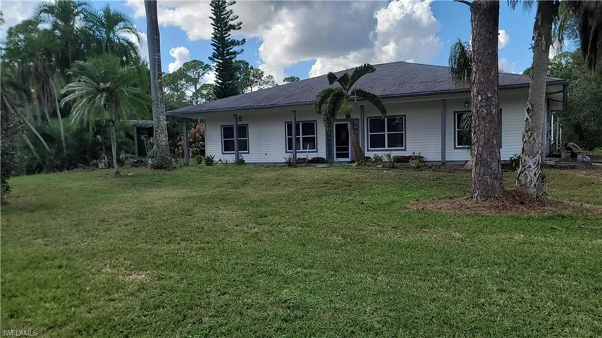 Rear view of property with a lawn and a shingled roof
