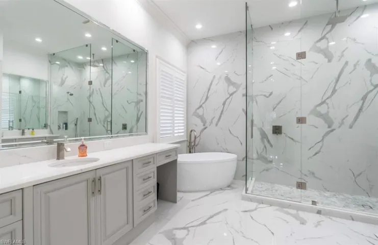 Full bath featuring stone wall, vanity, recessed lighting, a marble finish shower, and a soaking tub