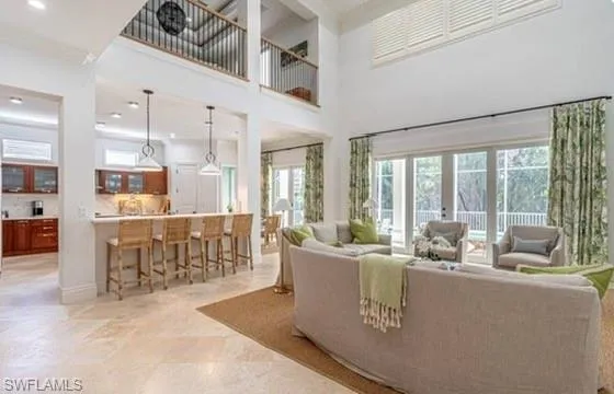Living area with ornamental molding, a high ceiling, recessed lighting, and french doors