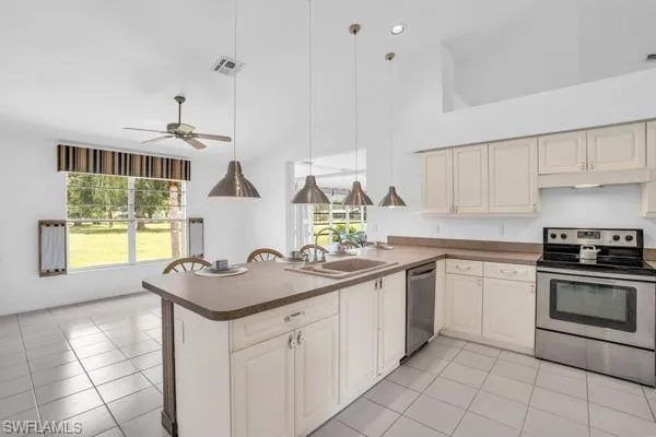 Kitchen with appliances with stainless steel finishes, light tile patterned floors, and plenty of natural light