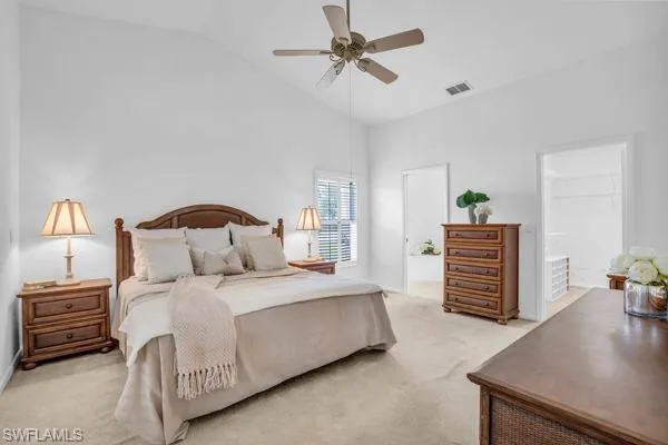 Carpeted bedroom featuring connected bathroom, high vaulted ceiling, and ceiling fan