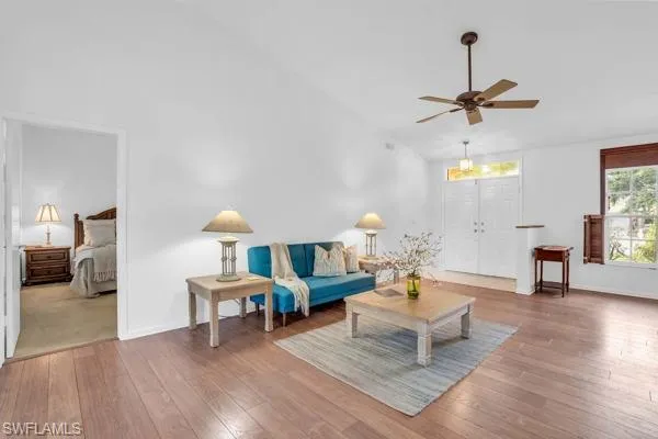 Living room with ceiling fan, carpet flooring, and high vaulted ceiling