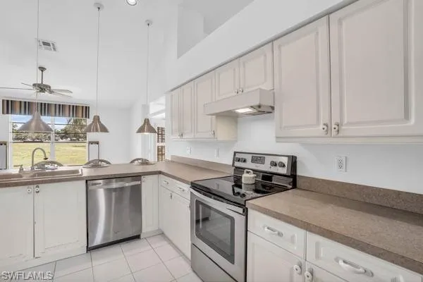 Kitchen with ceiling fan, stainless steel appliances, white cabinets, sink, and light tile patterned floors