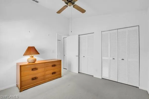 Bedroom with multiple closets, high vaulted ceiling, carpet floors, and ceiling fan
