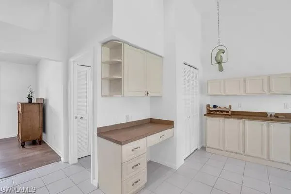 Kitchen featuring light tile patterned flooring, built in desk, cream cabinetry, and a towering ceiling