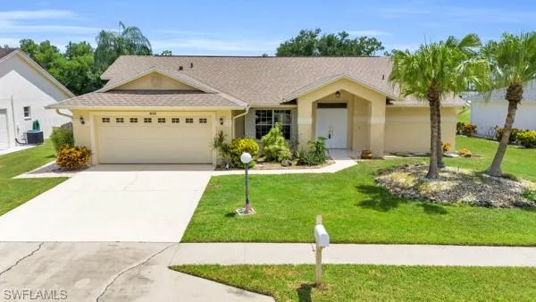 Ranch-style home featuring a garage and a front lawn