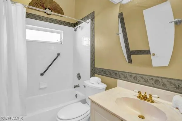 Full bathroom with vanity, shower / bath combo with shower curtain, and toilet