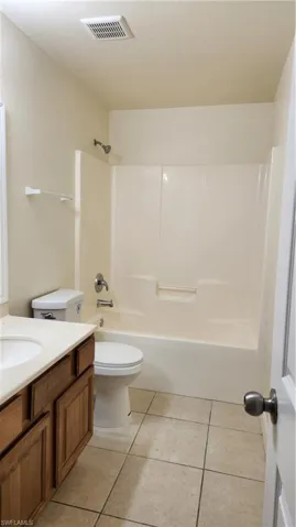 Full bath featuring vanity, light tile patterned floors, and shower / bath combination